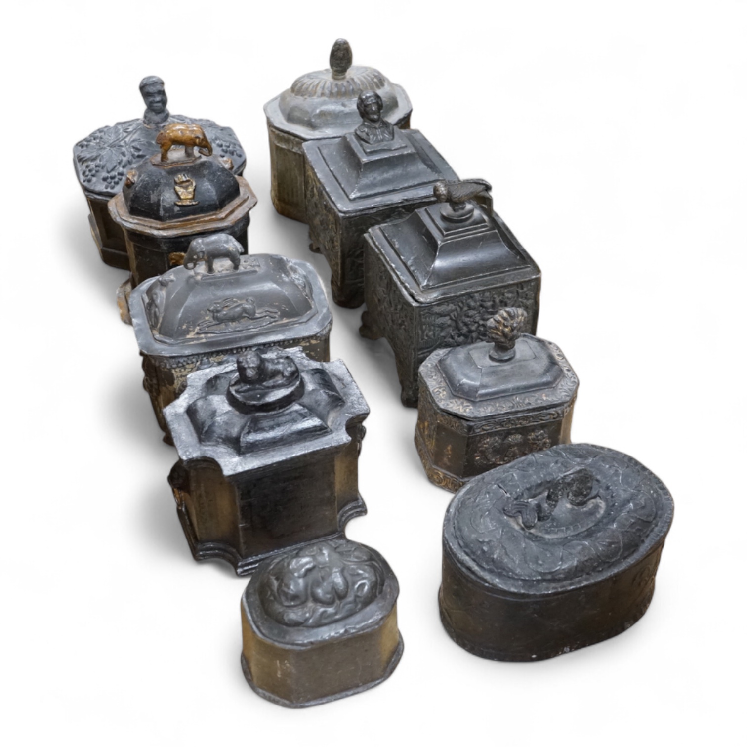 A collection of ten early 19th century lead tobacco boxes, one in the form of a monument with lion knop, largest 14cm wide